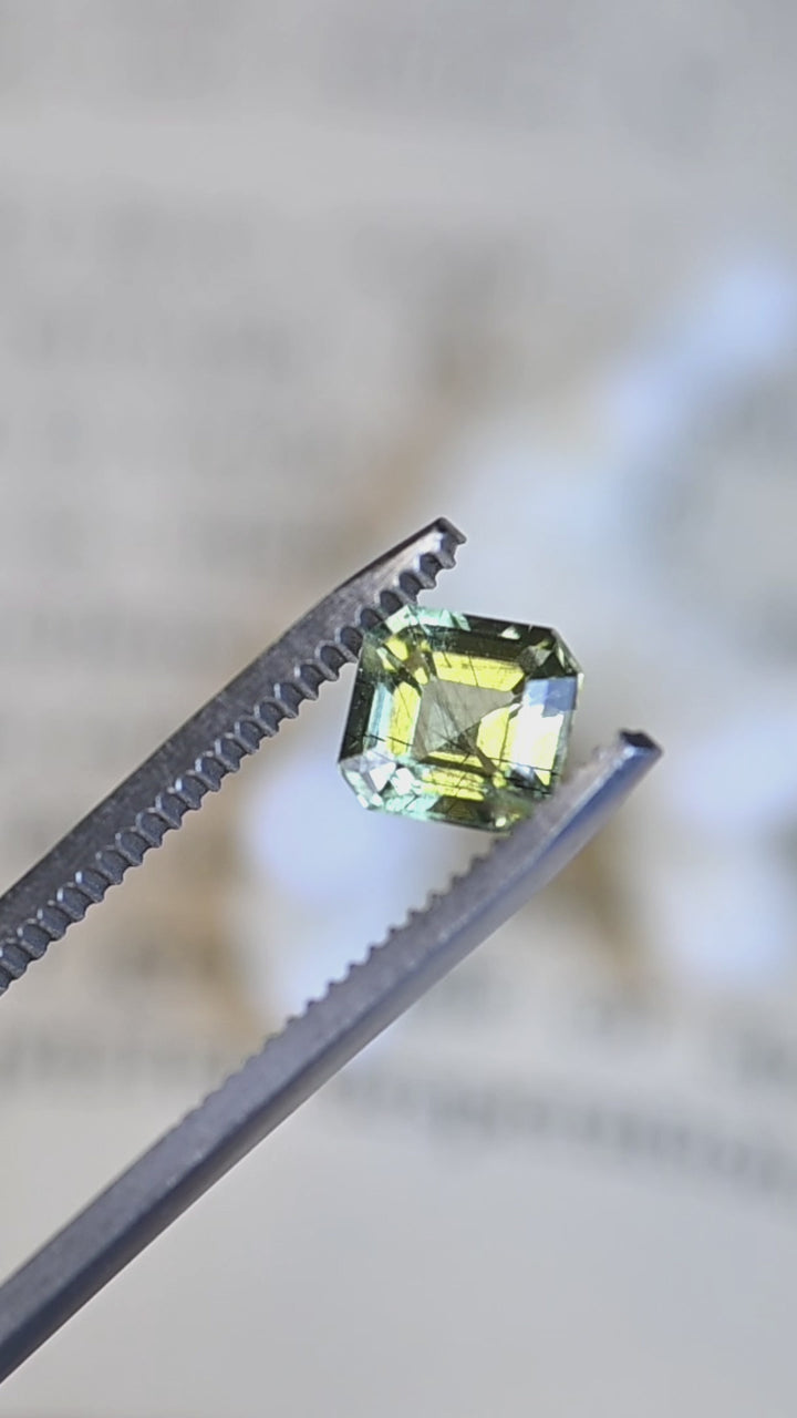 A close-up rotating view of this custom Asscher cut peridot from Pakistan, showcasing its architectural step facets, lively lime-green color, and natural crystal character.