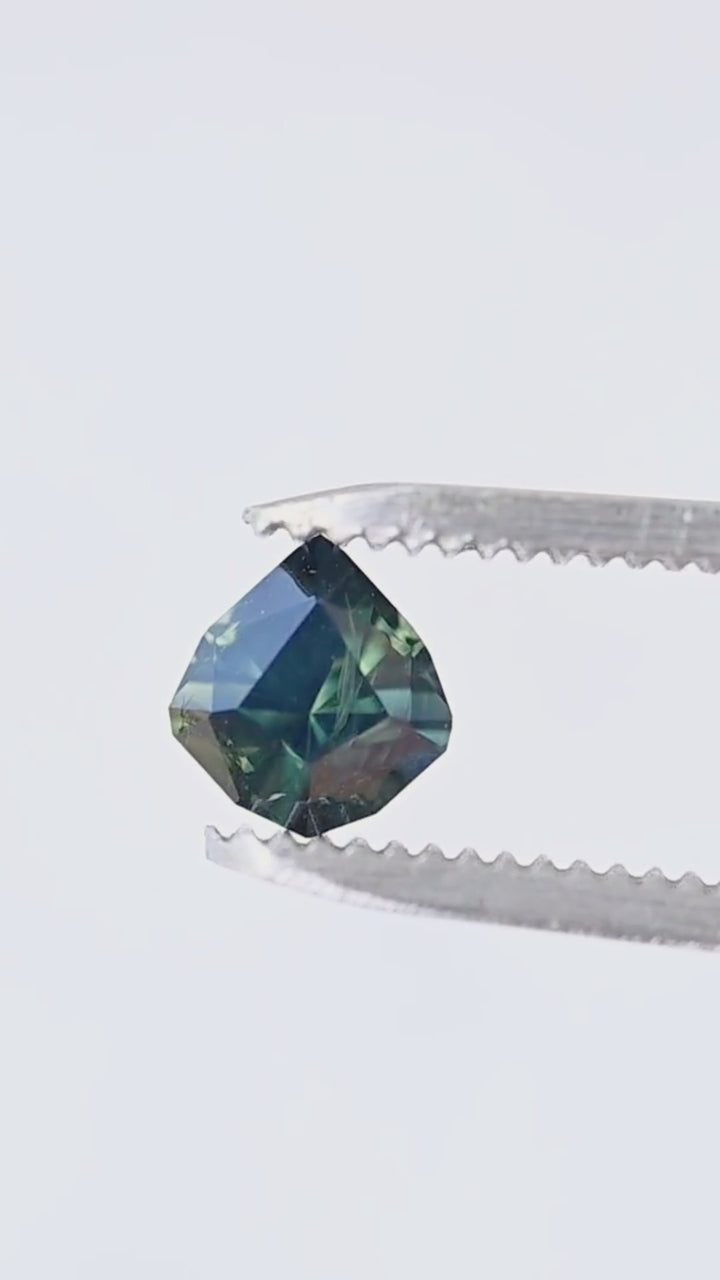 Explore the custom geometric pear cut, saturated green-blue color and changing facet reflections of this untreated 1.26ct Australian sapphire in a close-up tweezer video.