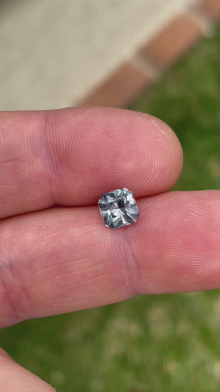 Video showcasing the exceptional quality of a teal, blue, and gray sapphire, focusing on its modified Asscher cut and the reflective properties of its facets.