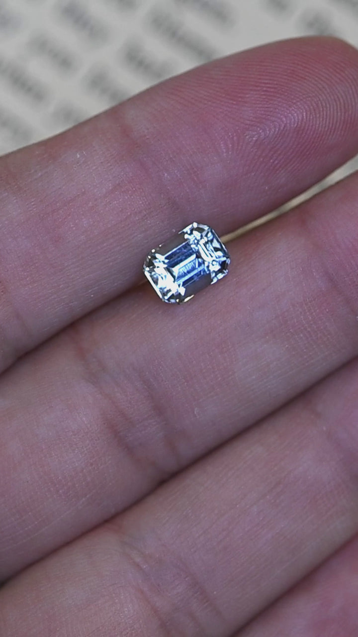 A close-up view of this untreated Colorado aquamarine showcasing its precision custom octagonal step cut, crisp facet alignment, and luminous baby blue color as it rotates in hand.