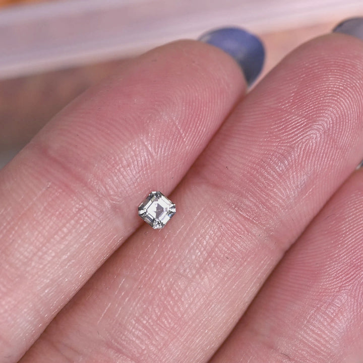 Rotating loose blue-teal Montana sapphire in an Asscher cut, showing step-cut brilliance and natural green undertones from Montana.