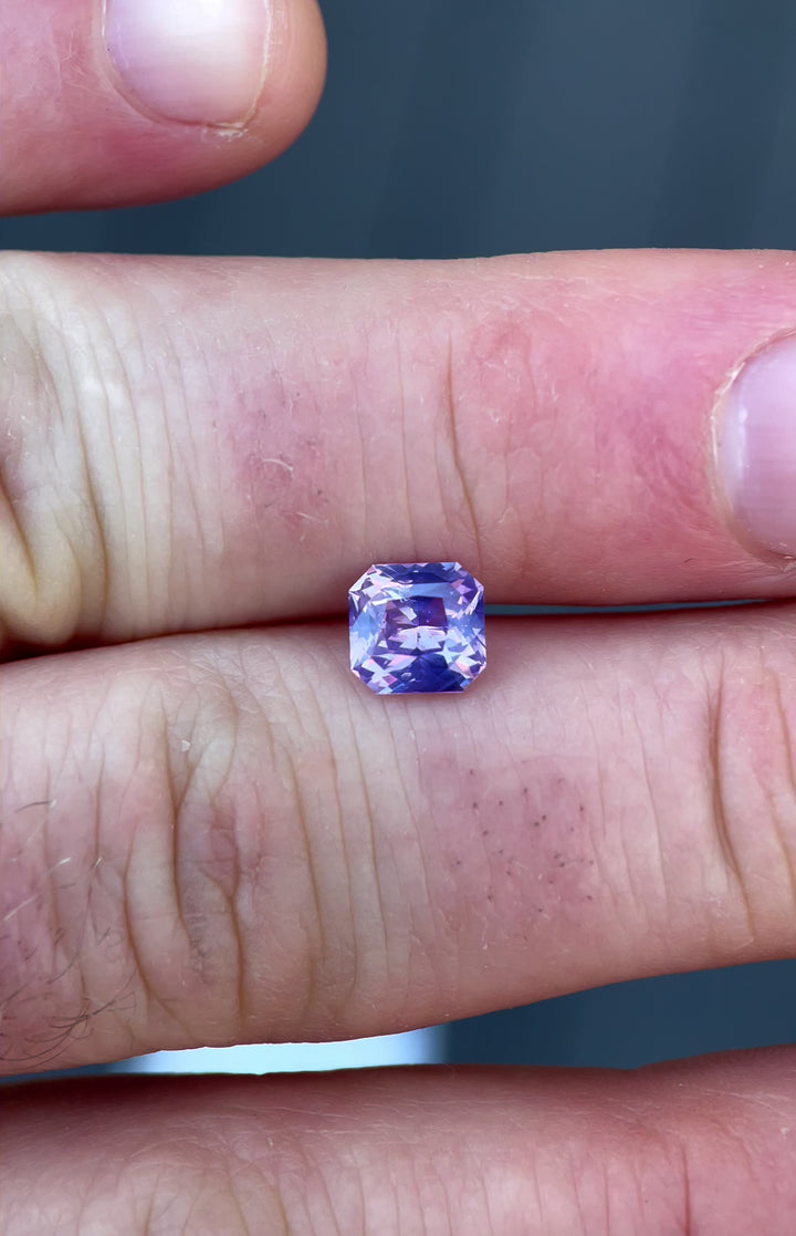 Admire the brilliance of a 1.57-carat opalescent sapphire in a custom radiant cut. Ethically sourced from Sri Lanka, this untreated gemstone radiates pink and purple tones, ideal for fine jewelry.