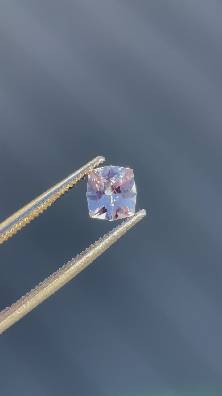 A detailed 360-degree video showcasing the vibrant pink peach hues and fancy cushion cut of a 1.04-carat sapphire, captured to emphasize its brilliance and untreated origin.