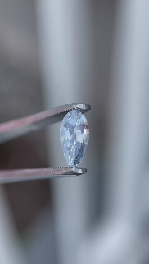 Video showcasing a light sage green sapphire, weighing 1.42 carats, from Sri Lanka. The gemstone is displayed in motion, revealing its custom modified pear shape and natural, untreated hues against varying backgrounds.