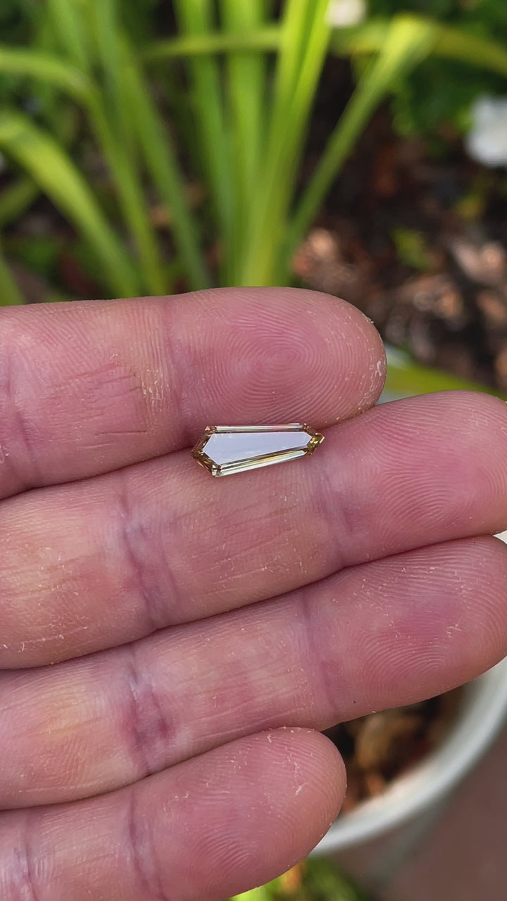 A close-up video of a 2.02-carat champagne fancy brown diamond, showcasing its elongated shield step cut and brilliant step-faceted reflections.