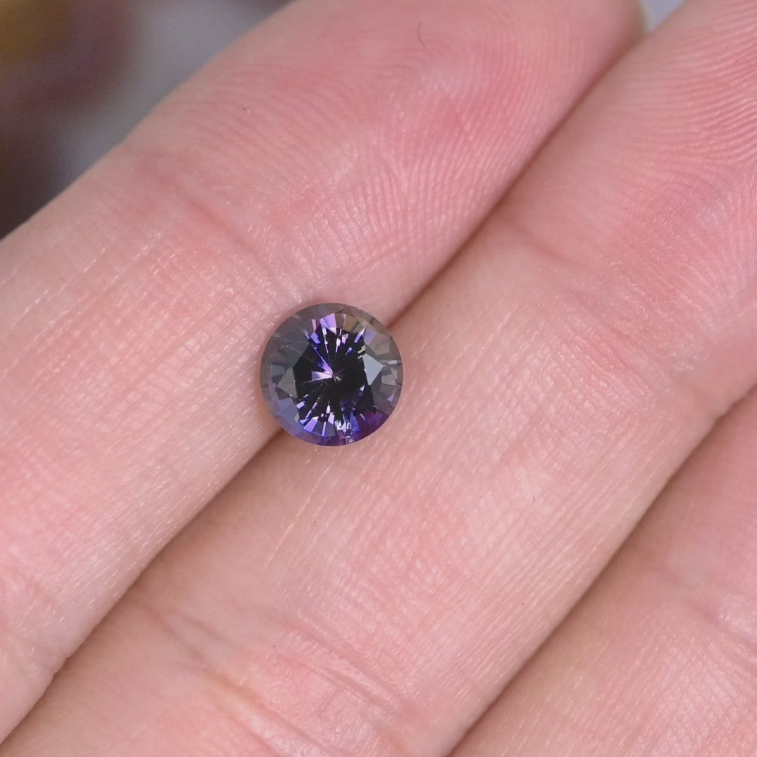1.19 carat untreated orange purple Tanzanite round brilliant rotating under natural light, Merelani Hills Tanzania gemstone showing vivid color shift and sparkle for custom jewelry