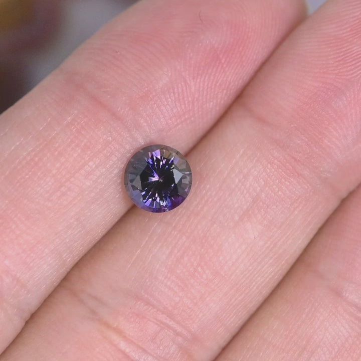 1.19 carat untreated orange purple Tanzanite round brilliant rotating under natural light, Merelani Hills Tanzania gemstone showing vivid color shift and sparkle for custom jewelry