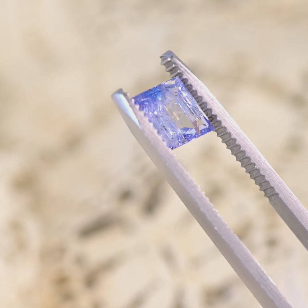 Close up video of 1.67ct emerald cut Tanzanite displaying step cut facets sparkle brilliance and mermaid purple blue green tones from Merelani Hills