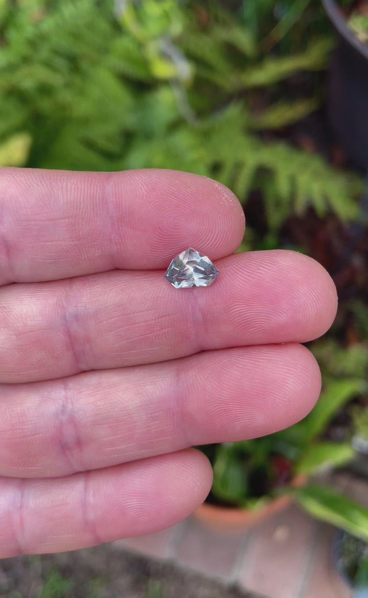 An up-close video of a 2.11-carat shield cut sapphire, focusing on its unique mix of gray, yellow, and teal colors. The video captures the light play across its precise facets and highlights its natural beauty