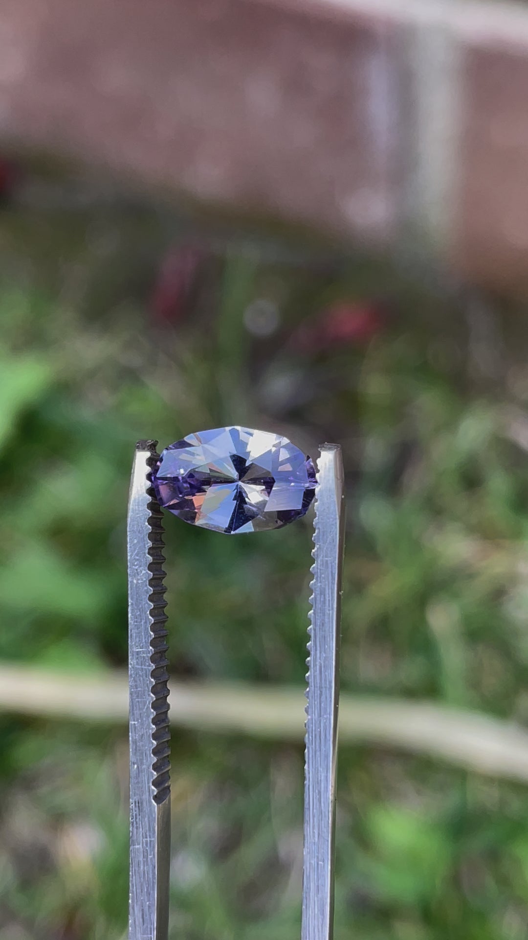 Video showcasing the brilliant gray, lavender, and purple shades of a 1.79 carat Tanzanite gemstone from Tanzania. The gemstone's custom geometric oval shape is highlighted as it rotates, providing a dynamic view of its clarity and vibrant colors.
