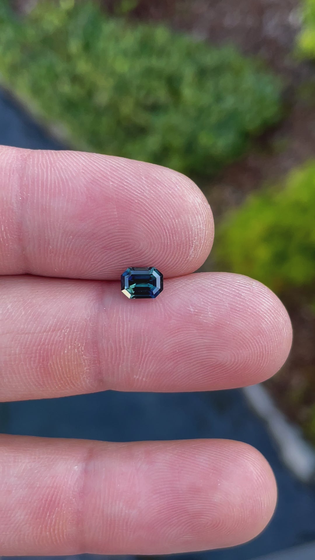 Handheld video view of a Nigerian sapphire in green and teal shades, expertly cut in an octagonal shape with step facets for maximum brilliance.