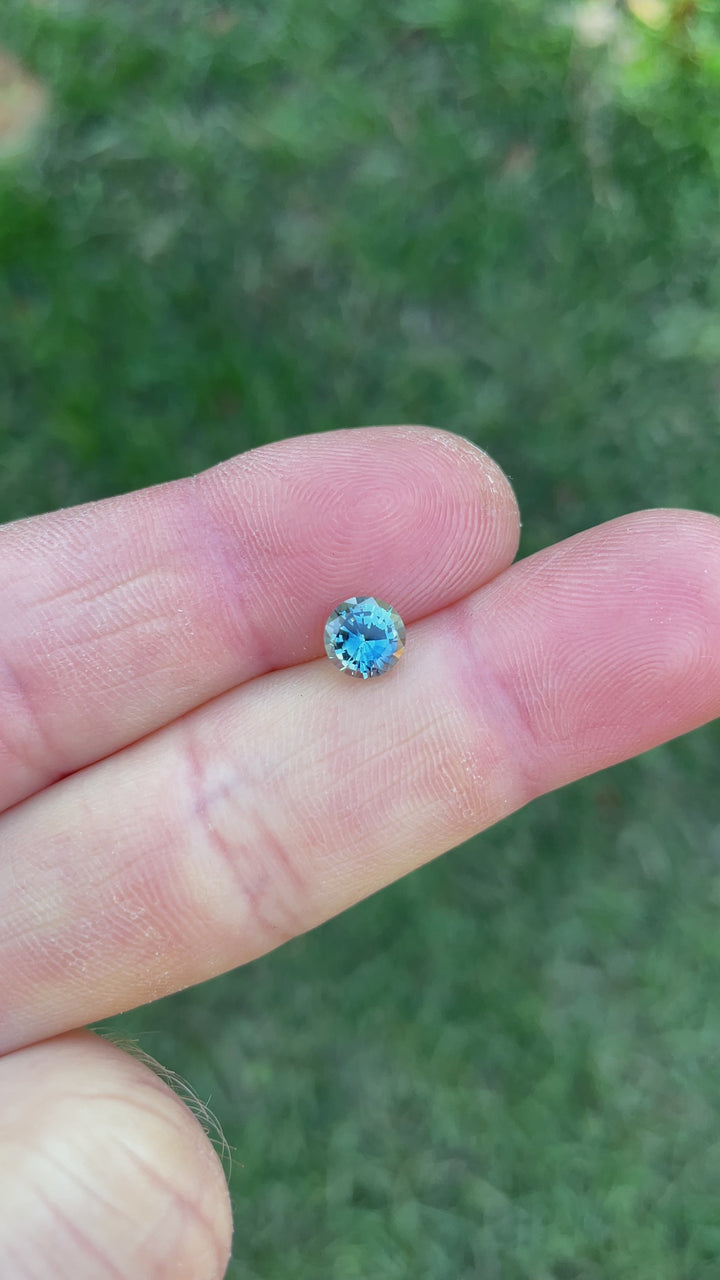 Video highlighting the color play and sparkle of a 1.08-carat round brilliant sapphire with blue, green, and teal tones from Madagascar.