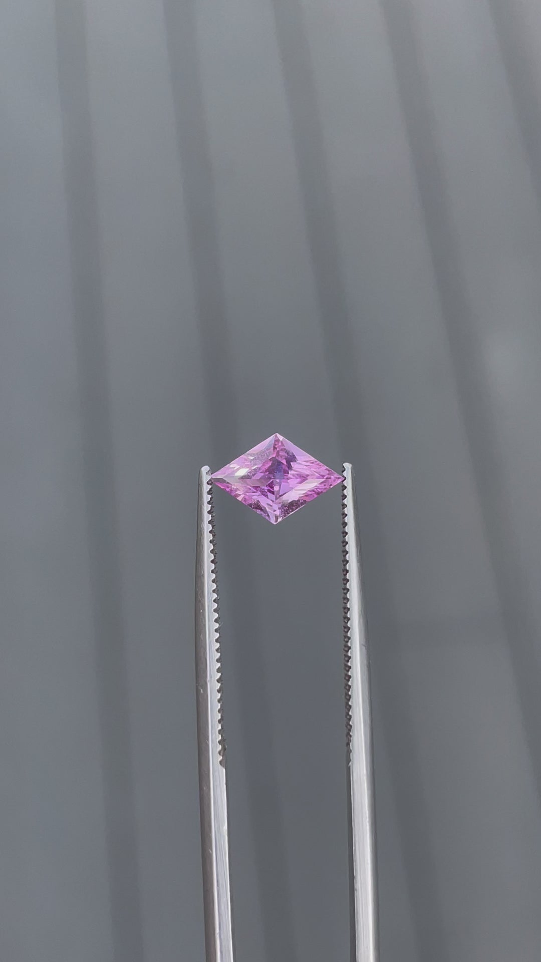 Video of a 1.06-carat purple sapphire in a kite step cut, held with tweezers to show its brilliance and delicate purple color. This Sri Lankan gemstone is untreated, enhancing its natural allure and making it a unique addition to any collection.