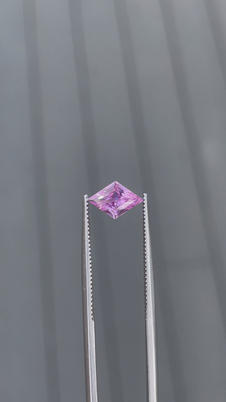 Video of a 1.06-carat purple sapphire in a kite step cut, held with tweezers to show its brilliance and delicate purple color. This Sri Lankan gemstone is untreated, enhancing its natural allure and making it a unique addition to any collection.