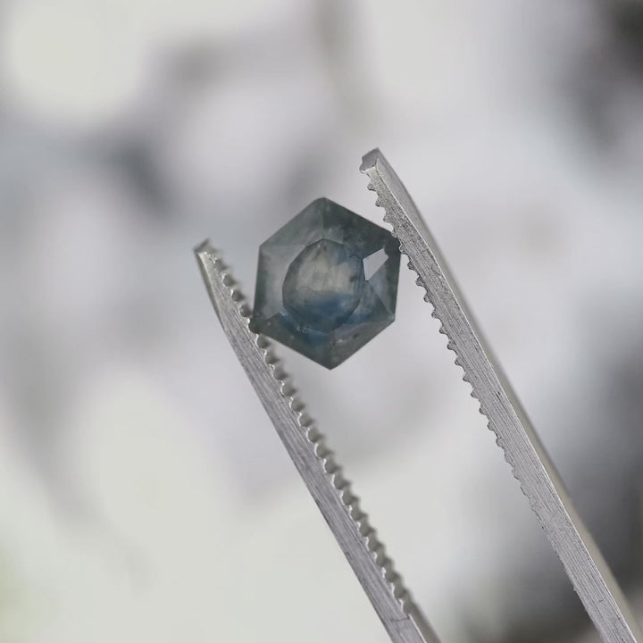2.00ct untreated Montana sapphire rotating in tweezers under natural lighting, hexagonal brilliant tablet cut showing teal blue gradient color shift and geometric faceting from El Dorado Bar Deposit USA