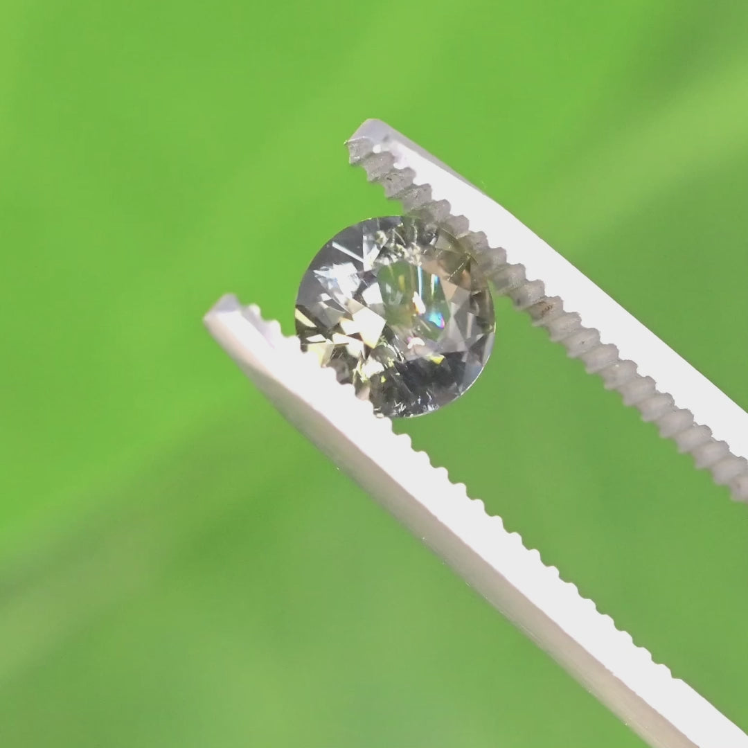 1.08ct blue and brown tanzanite custom modified round brilliant held in gem tweezers, highlighting sparkle, crown facets, and natural untreated gemstone from Merelani Hills Tanzania.