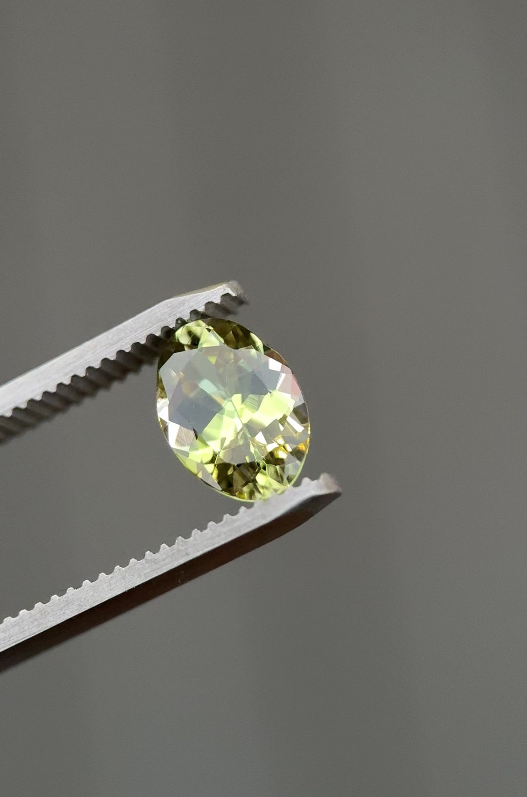 Close-up video of the 1.98-carat Tanzanite with yellow, teal, and green hues, moving through light to display its brilliance and untreated custom mix oval cut from Merelani Hills, Tanzania.