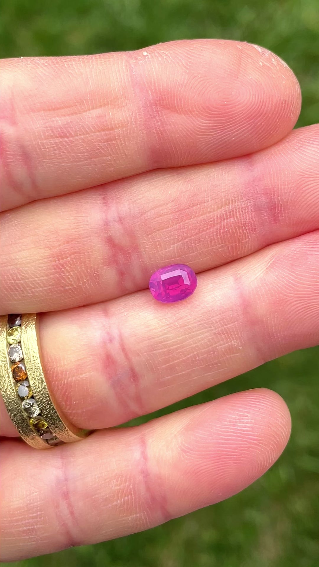 Macro video of a 1.53-carat opalescent sapphire, highlighting its oval cut, rich pinkish purple saturation, and clarity under sunlight.