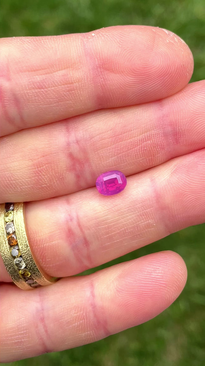Macro video of a 1.53-carat opalescent sapphire, highlighting its oval cut, rich pinkish purple saturation, and clarity under sunlight.