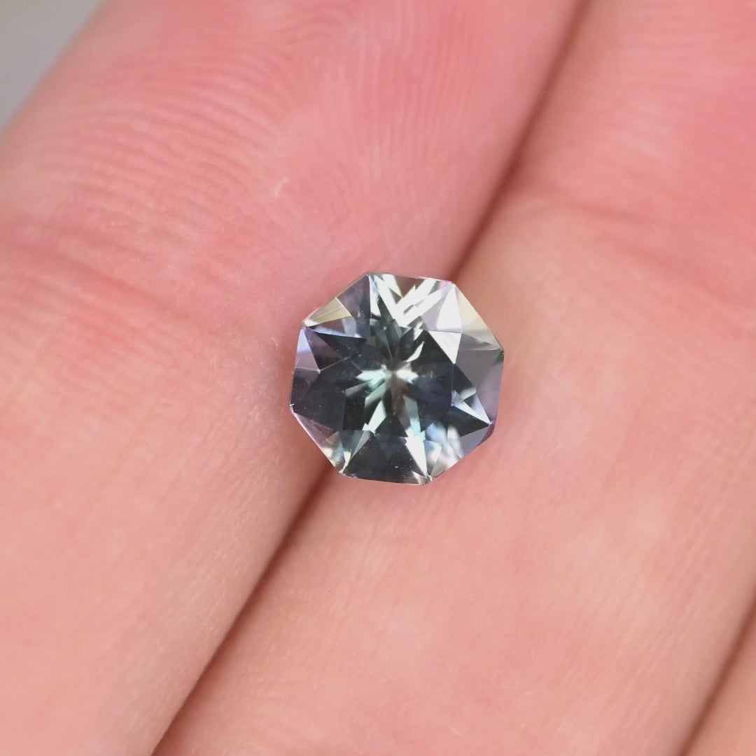 2.45 carat untreated gray lavender blue Tanzanite oval rotating under natural light, custom modified mix brilliant cut from Merelani Hills Tanzania showing trichroic color shift and brilliance for custom jewelry