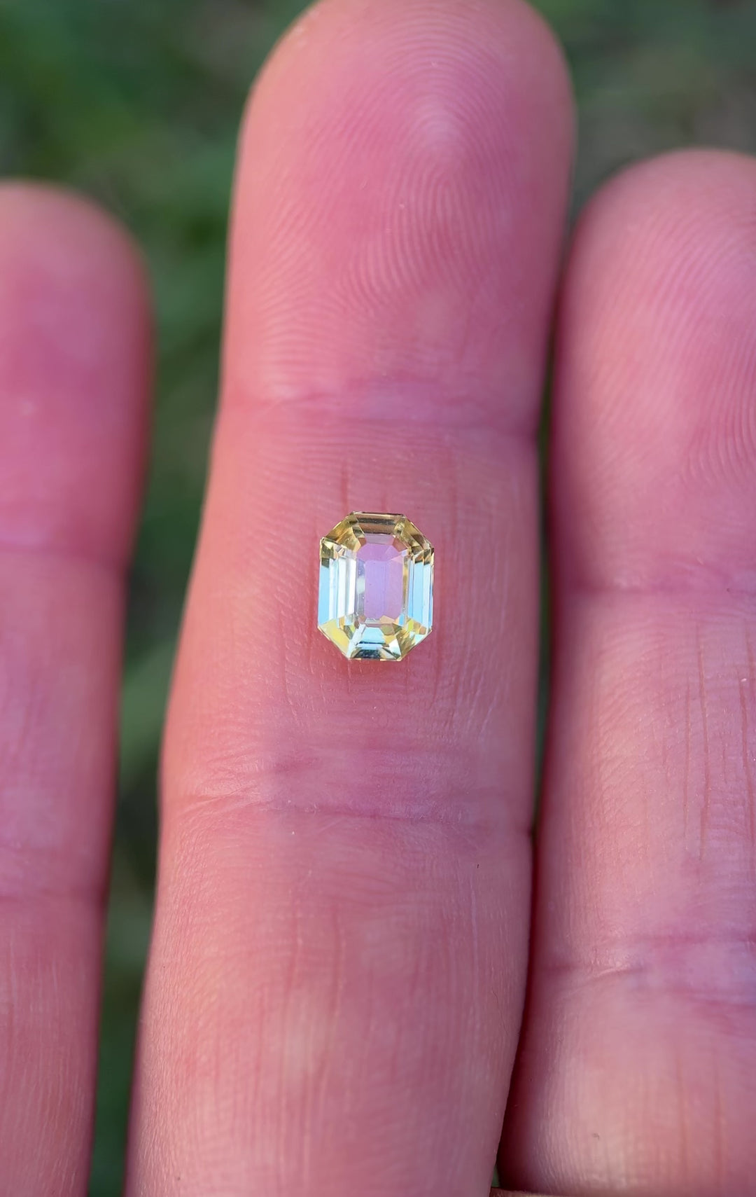 Close-up video of 1.55 carat yellow sapphire resting on fingertips, revealing shifting golden reflections and fine craftsmanship of the precision antidote emerald cut, untreated sapphire from Madagascar.