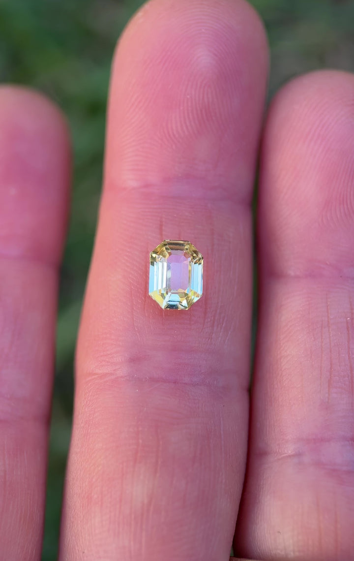 Close-up video of 1.55 carat yellow sapphire resting on fingertips, revealing shifting golden reflections and fine craftsmanship of the precision antidote emerald cut, untreated sapphire from Madagascar.