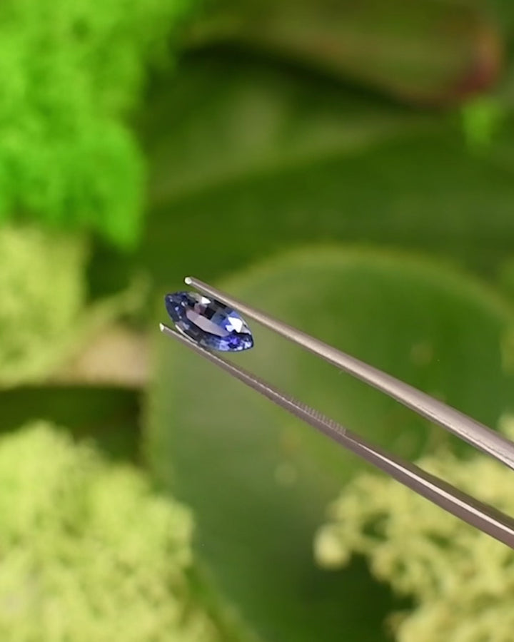 Macro video of 1.24CT vivid blue sapphire rotating in gemstone tweezers under natural sunlight, emphasizing its brilliance, clarity, and vivid blue color in a precision marquise mixed cut, unheated sapphire from Sakaraha, Madagascar.