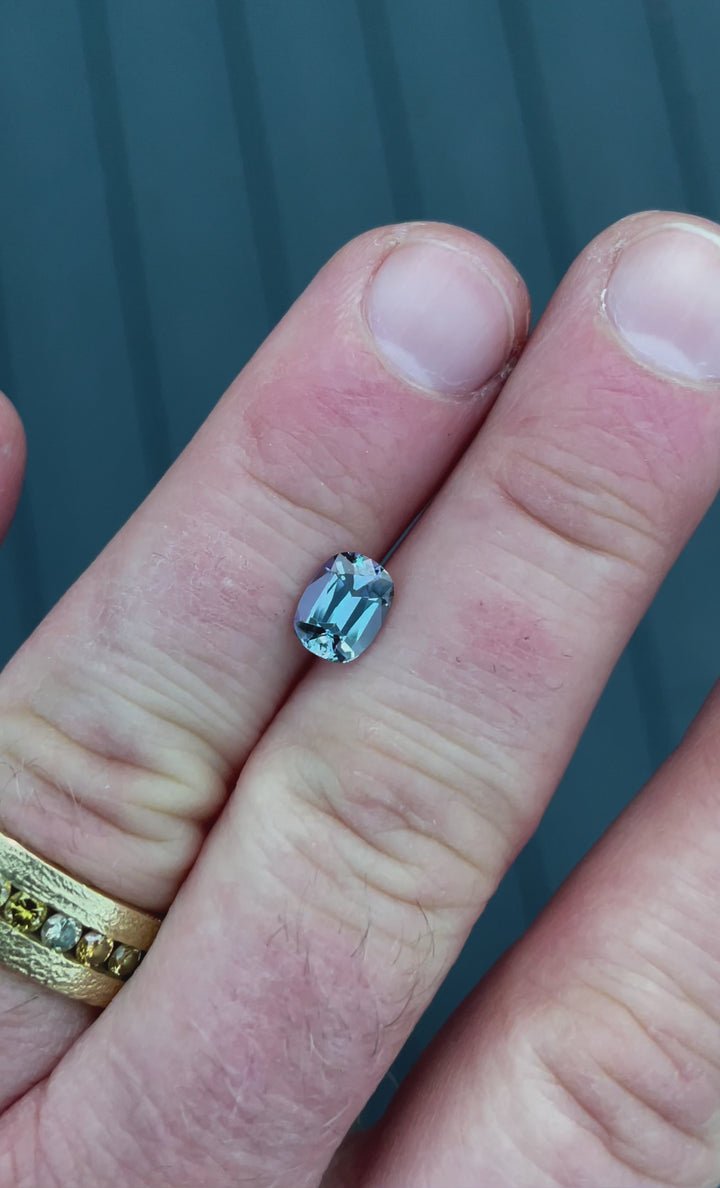 A 1.36-carat Tanzanite gemstone in a modified cushion cut, shimmering in teal, blue, and violet hues as it moves under natural light. This rare, untreated gem from Merelani Hills, Tanzania, showcases exceptional brilliance and clarity.