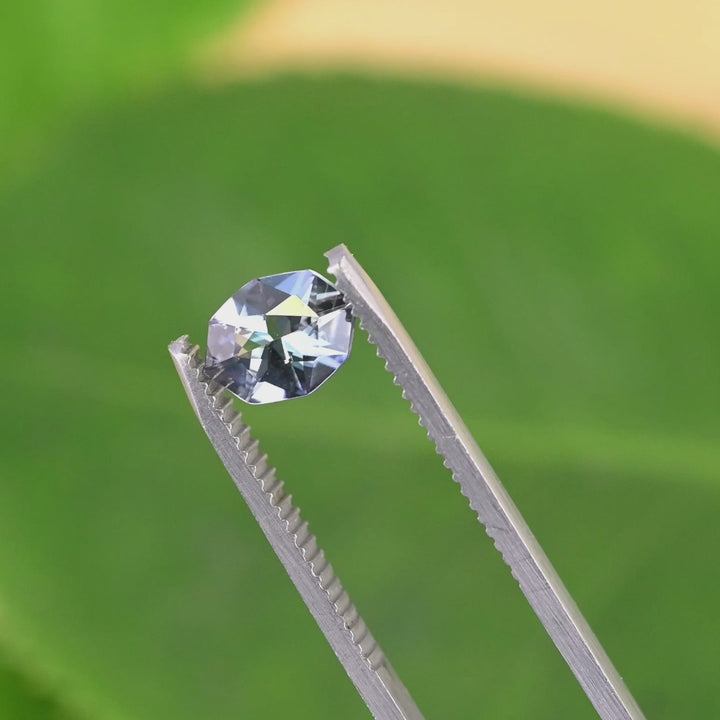 Close-up video of 1.27ct teal blue purple Tanzanite custom geometric marquise cut rotating in tweezers, precision faceted Merelani Hills gemstone showing vivid brilliance and color shift