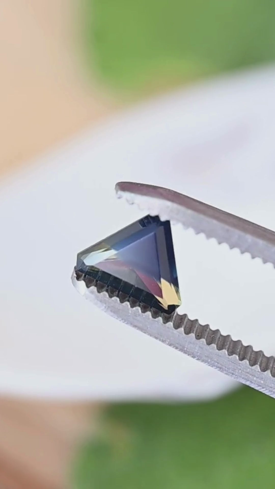 A close-up view of the angular facets and natural blue, yellow and green color zoning in this untreated 1.28ct precision trillion cut sapphire from Madagascar.