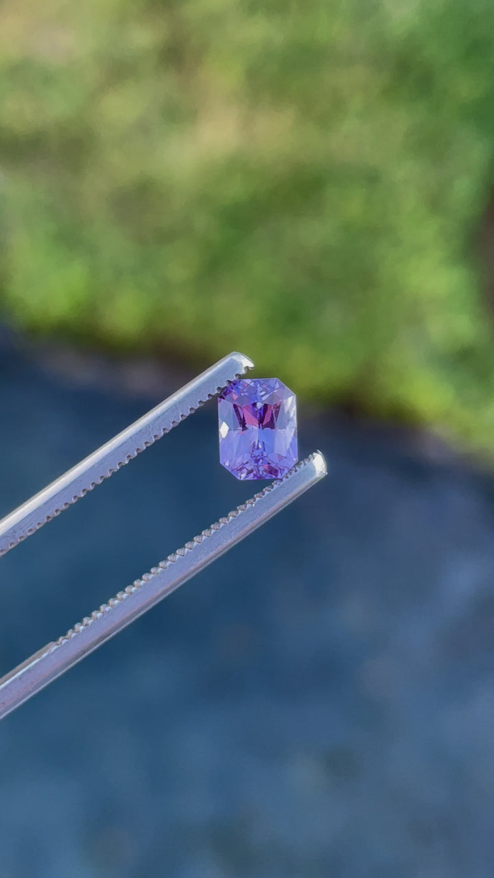 Dynamic video showcasing a 1.05 carat radiant cut sapphire with vivid pink and purple hues, emphasizing its clarity and precise geometric facets, sourced from Sri Lanka.