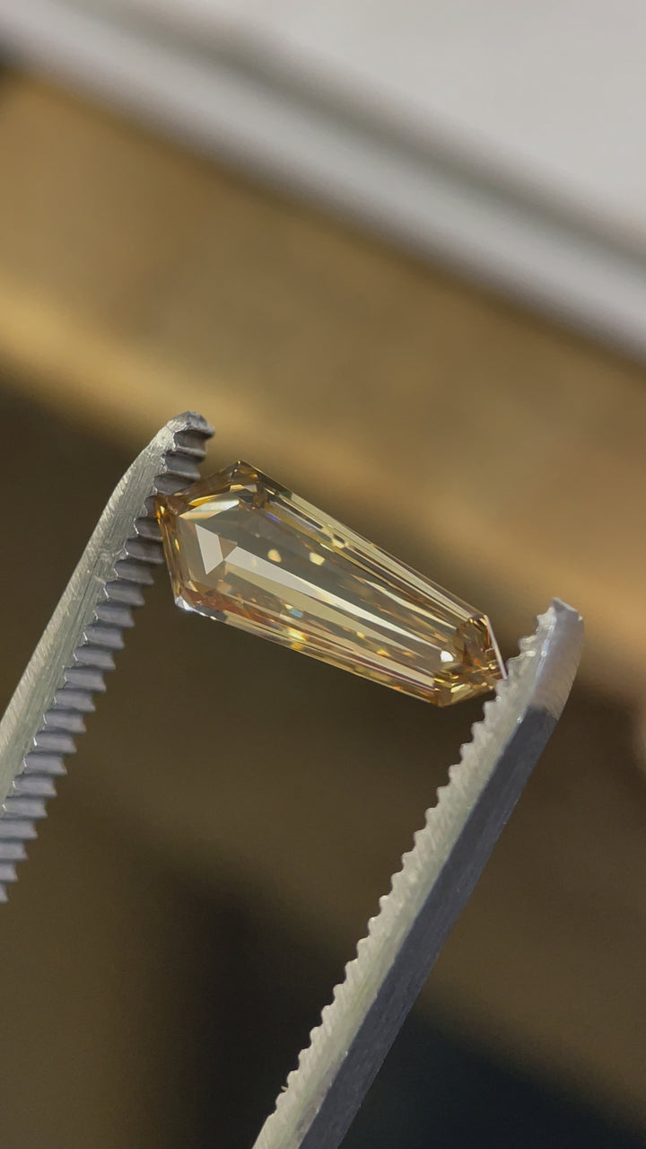 A rotating view of a VVS2 clarity champagne brown diamond, highlighting its natural golden hues and intricate step cut.