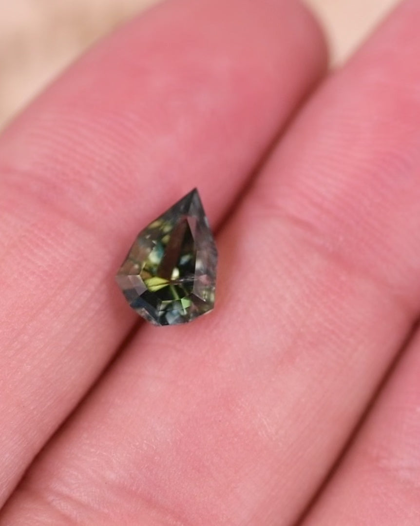 Macro video of 1.64 carat yellow green teal tanzanite turning to show light reflection and brilliance, capturing its precision-cut shield shape and unheated natural beauty from Merelani Hills, Arusha Region, Tanzania