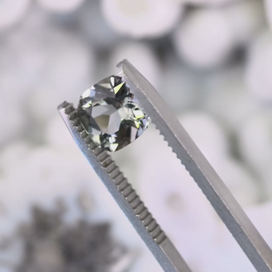 Close-up video of 2.74ct square radiant Tanzanite held in tweezers, precision cut purple green gemstone from Tanzania displaying clarity, sparkle and trichroic color change