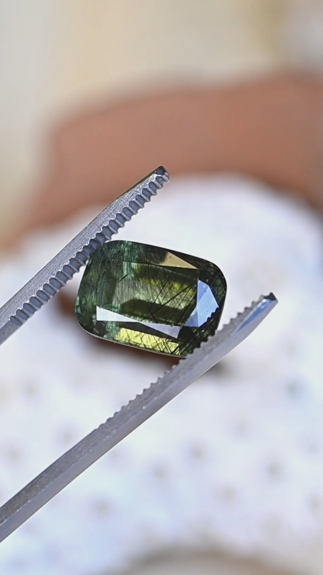 Watch this untreated 8.25 carat peridot from Skardu, Pakistan rotate in natural light, revealing its deep forest green color, elongated cushion mix cut, and captivating natural needle inclusions.
