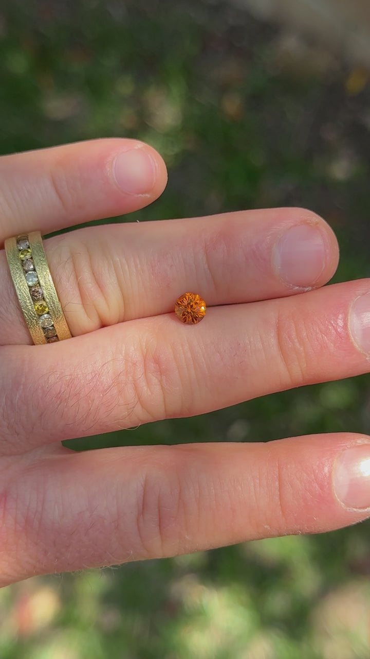 360-degree rotation of round brilliant Hessonite garnet in natural light capturing vivid yellow-orange sparkle