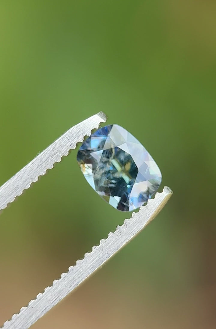 Video showing a rotating view of a 1.23-carat teal to purple sapphire with custom antique-style cushion cut, emphasizing its dynamic color shift.