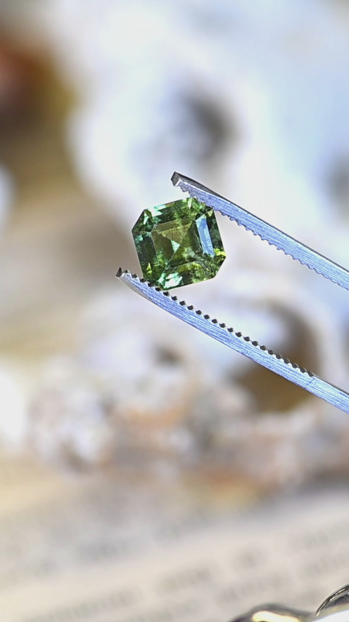 A rotating close-up of this custom Asscher cut peridot from Pakistan, showcasing crisp step facets, exceptional lime-green brilliance, and naturally occurring internal crystal features.