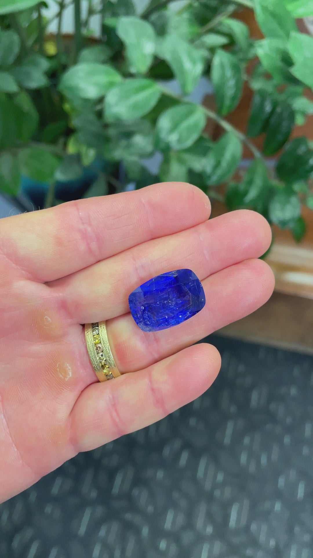 Video of a 27.31ct tanzanite in cushion cut, revealing its brilliance, depth of color, and untreated beauty from multiple angles in hand.