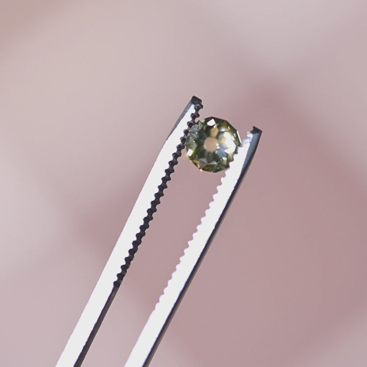 Fancy yellow brown diamond turned in tweezers under natural light, showing brilliance, depth, and subtle fluorescence character.