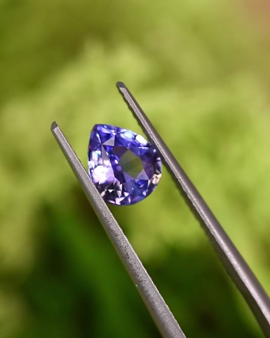 Macro video of 1.51CT violet purple pink sapphire rotating in tweezers, revealing vibrant light reflection and depth of color in the pear brilliant cut, unheated gem from Sakaraha, Madagascar.