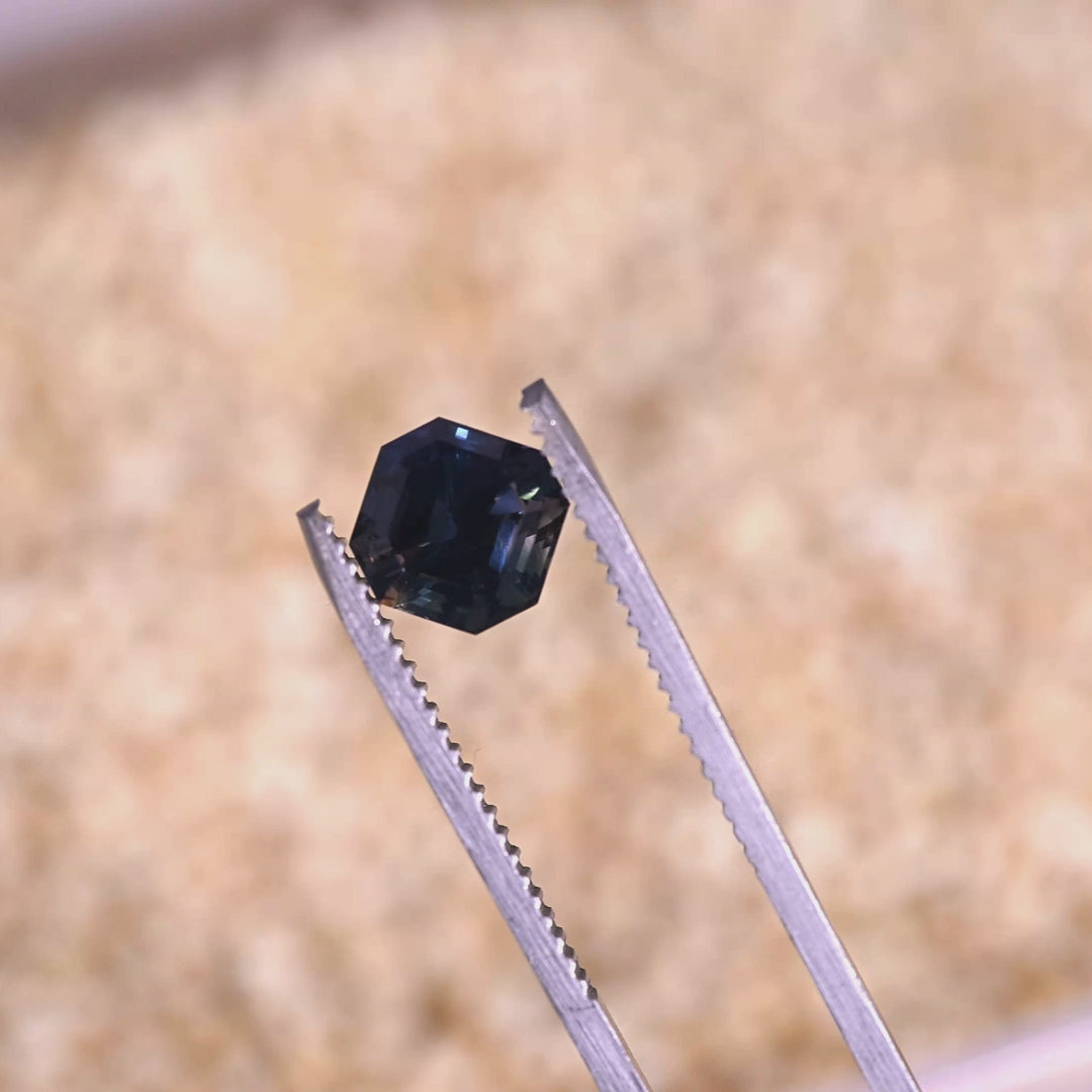 Rotating loose color change sapphire from Gombe, Nigeria showing the precision Asscher cut and transition from teal blue to mauve purple in changing light.