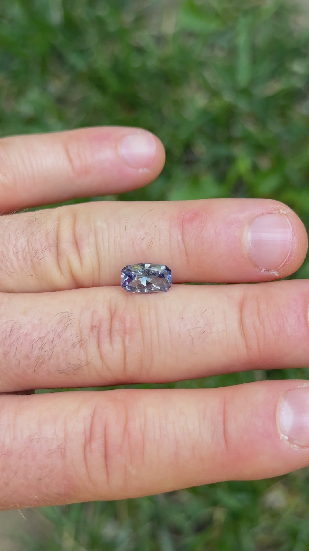 Outdoor video of 1.84ct Tanzanite in hand, displaying natural brilliance and color shift from green to violet under sunlight.