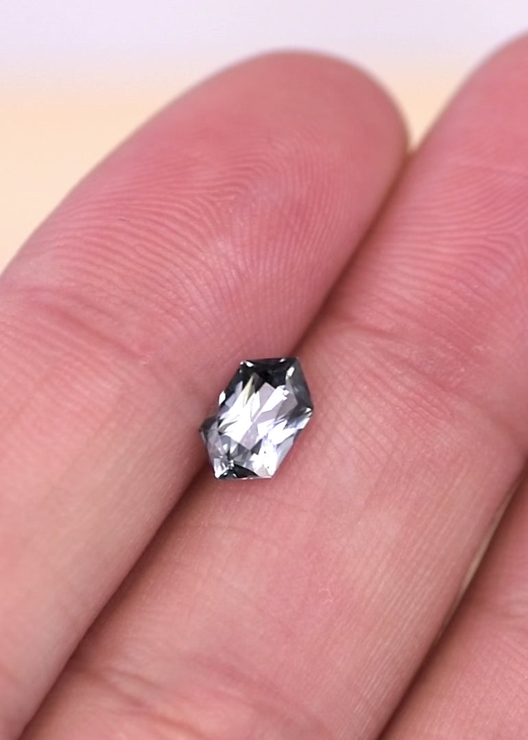 Macro video showing elongated hexagon seafoam grey blue sapphire as it moves under light, highlighting crisp facet junctions, pastel blue-gray tones, and unheated natural origin from Madagascar