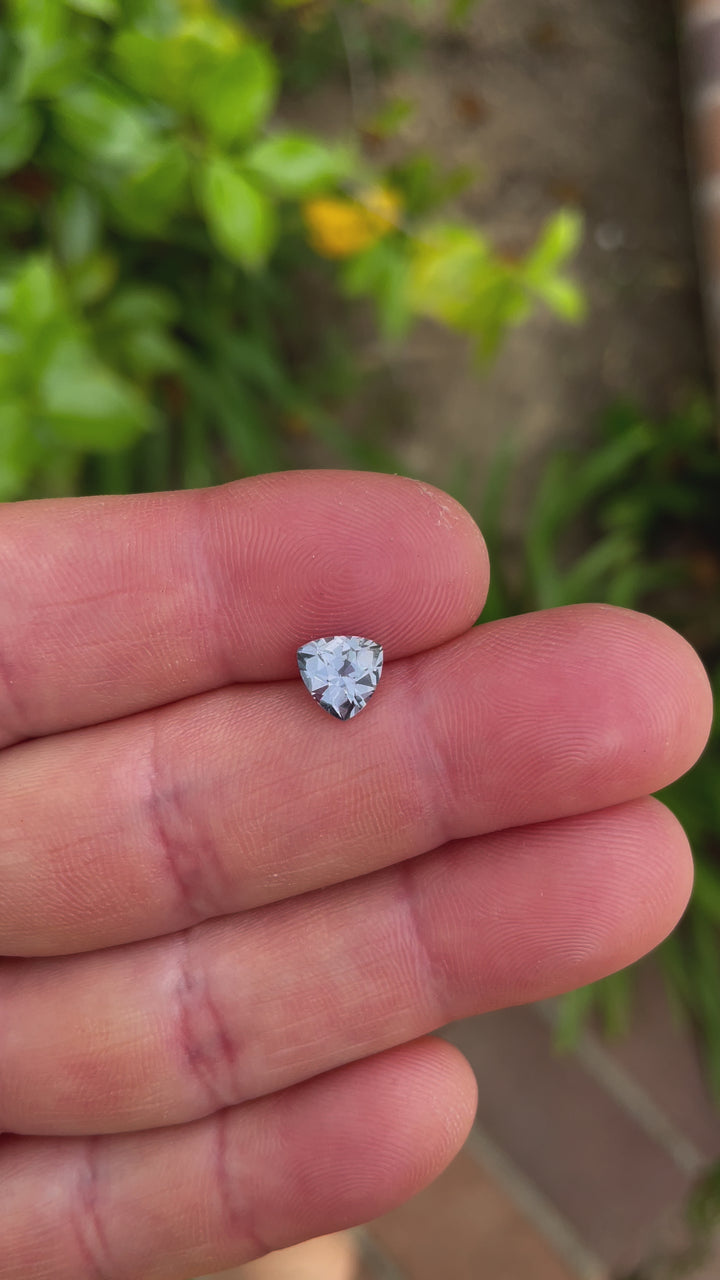 A video showcasing a 1.50-carat custom trillion-cut sapphire with subtle gray, purple, and blue hues. The stone's facets are displayed under varying angles, revealing its intricate precision and natural beauty. The sapphire is untreated and sourced from the Umba River, Tanzania.