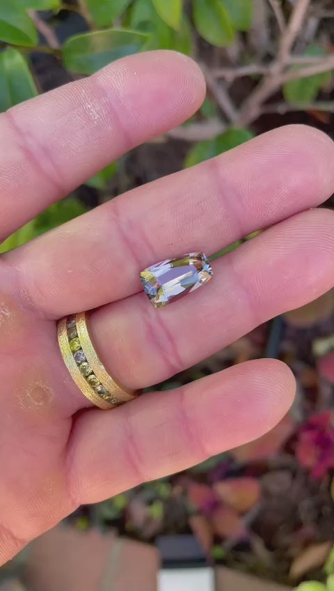 Video displaying the rotation of a 4.98-carat Tanzanite from Tanzania, emphasizing its custom tapered shield mix cut and the distinct purple and champagne color shifts.
