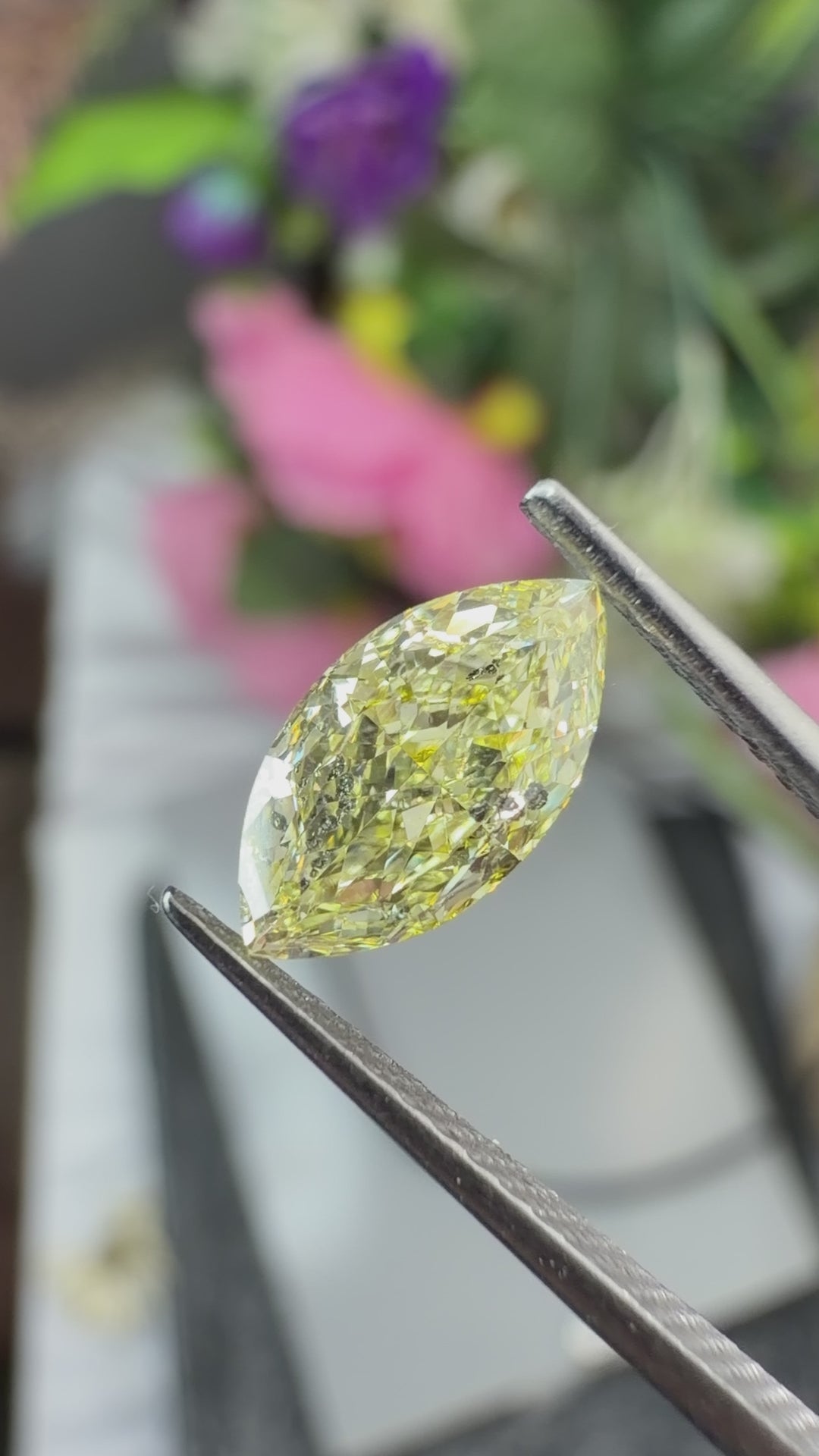 Natural fancy yellow marquise cut diamond rotating in gem tweezers under natural light