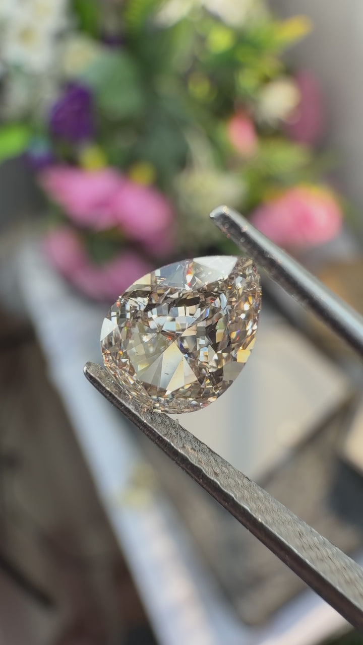 Natural light pink brown pear cut diamond held in gem tweezers rotating under natural light