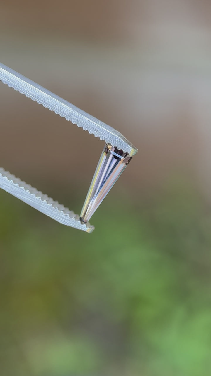 360-degree video of a 0.67-carat Tanzanite in a custom elongated tapered baguette cut, reflecting multi-color hues from Merelani Hills.