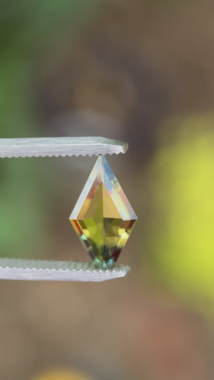 Rotating video of a 2.38ct kite double cut parti sapphire with vibrant yellow and blue colors, showing the gem's brilliance and precision facets from all angles.

